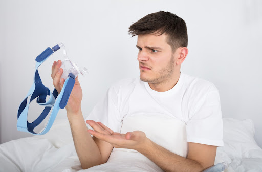 Worried man looking at a CPAP machine needing an alternative treatment
