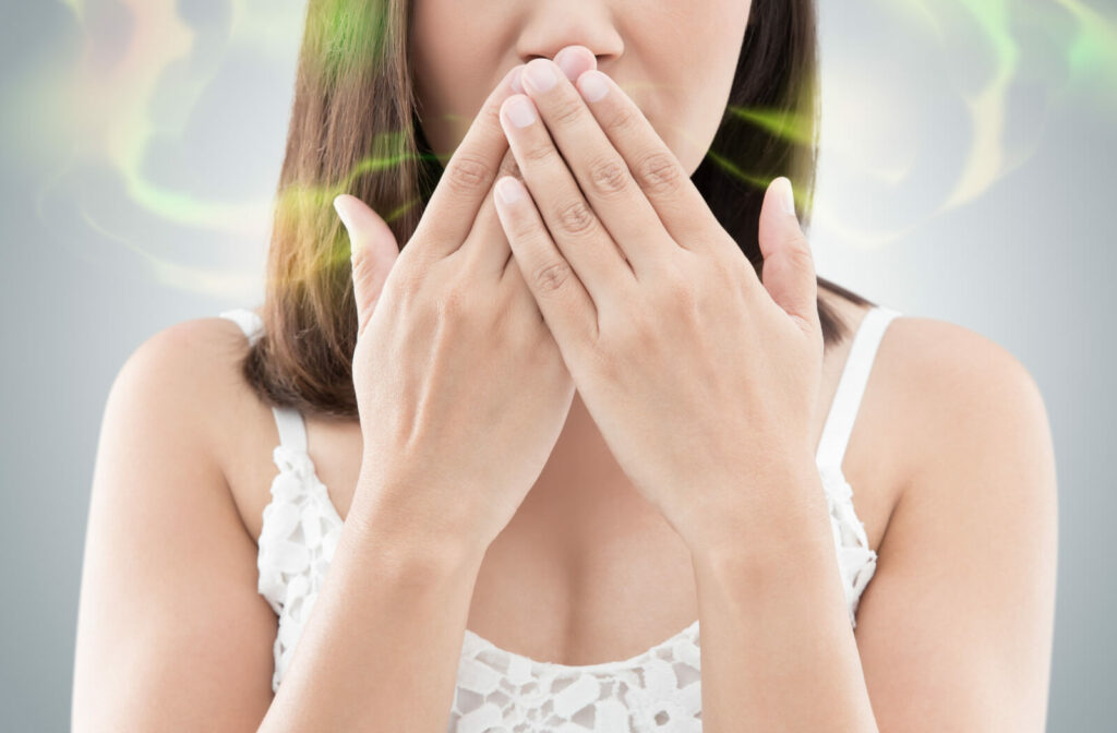 A woman covering her mouth, an illustration of having bad breath.