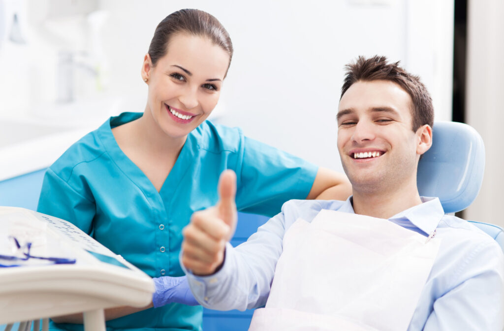 A man smiling with his female dentist, giving a thumbs up while in the dental chair.
