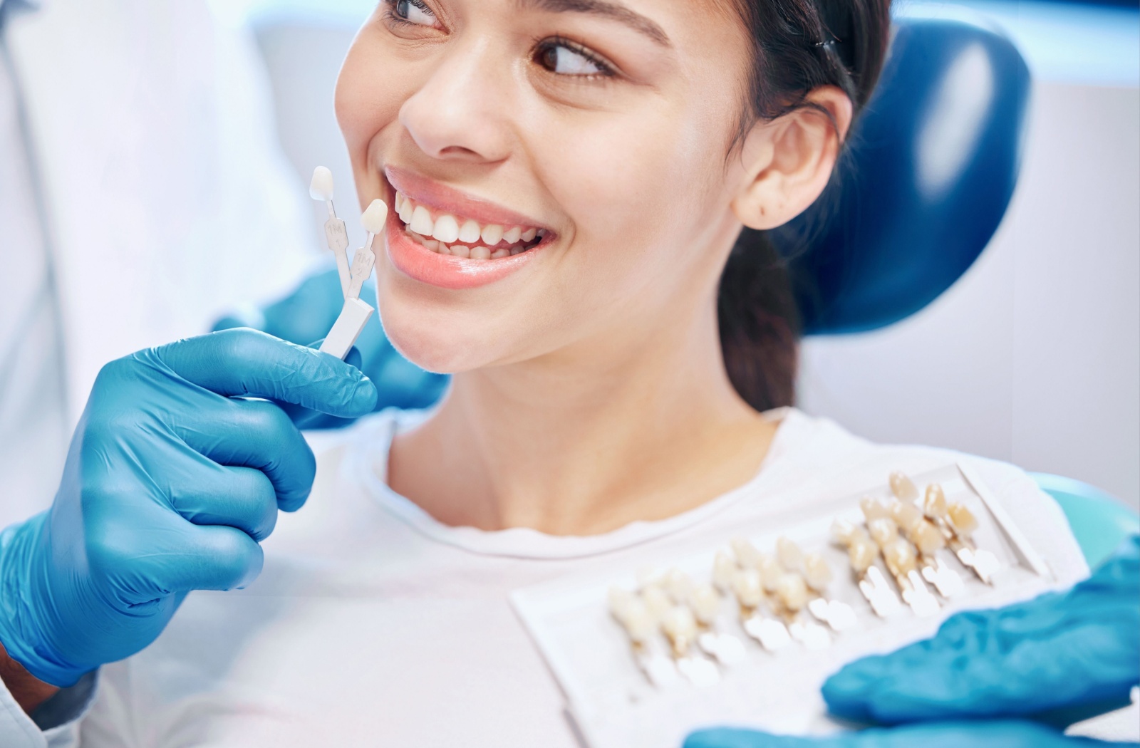 Woman selecting veneer shade at dental clinic.