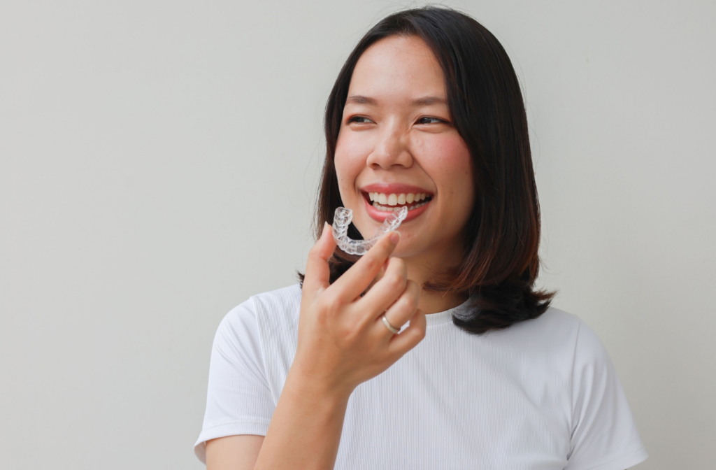 A person smiling holding up their invisalign.