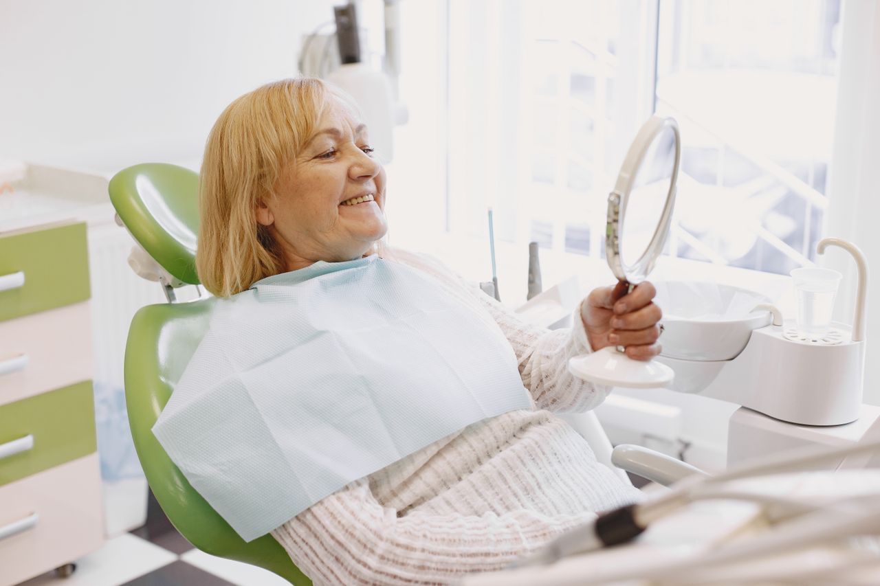 Woman checking her teeth in a mirror at the dentist