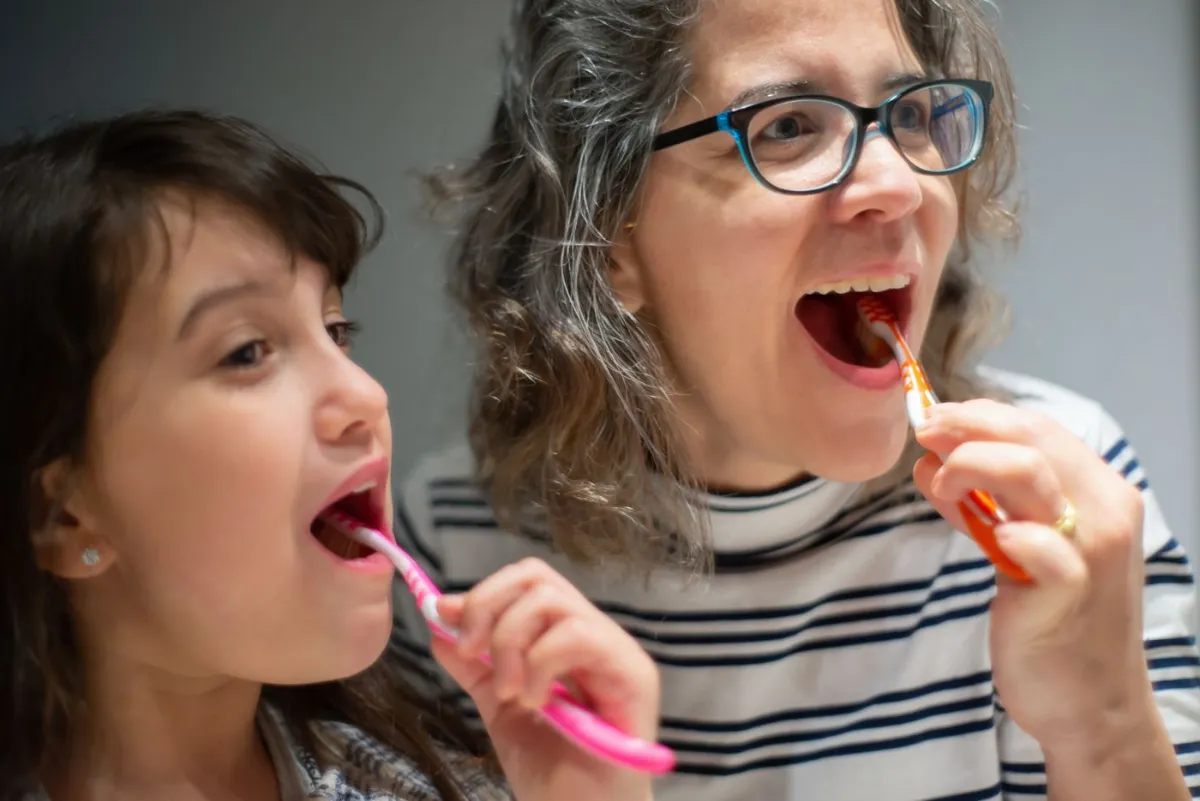 Mother and daughter brushing teeth, covered dental care with CDCP in Oakville