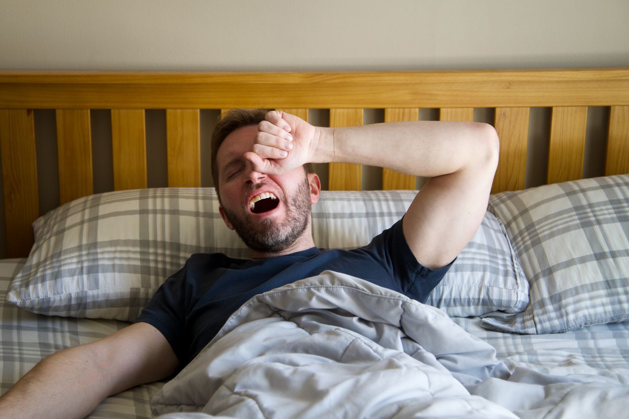 Man yawning and rubbing his eyes after waking up